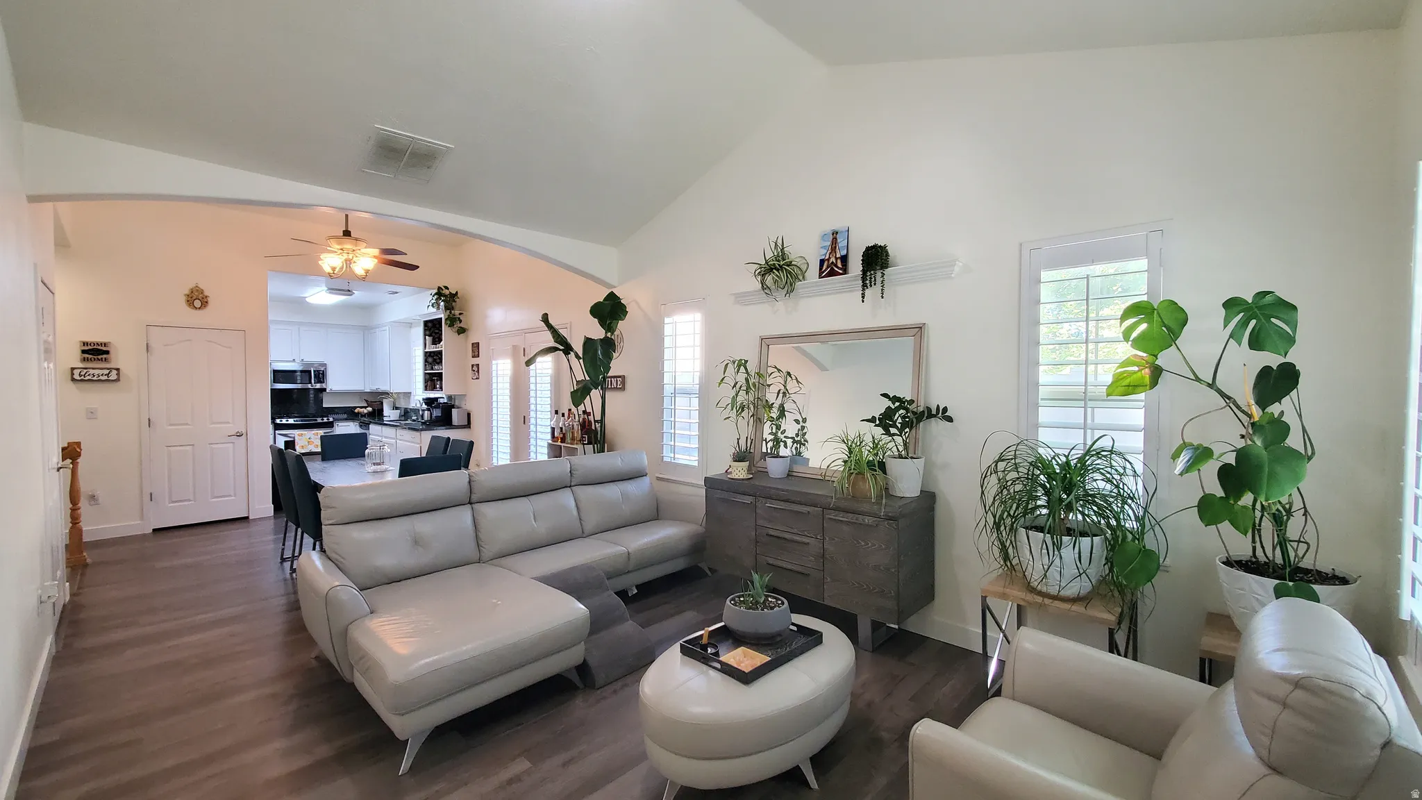 Spacious living area featuring vaulted ceilings, wood-finish flooring, and white plantation shutters
