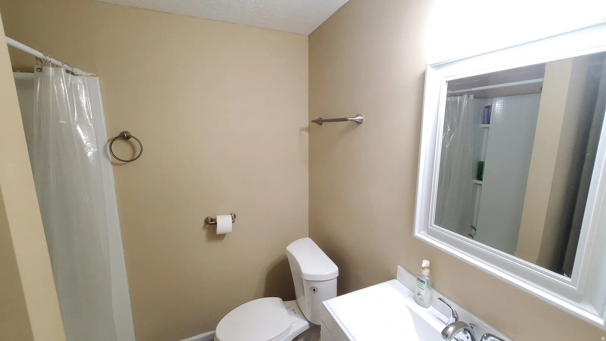 Bathroom with a white vanity and integrated sink, a framed rectangular mirror, and a white toilet