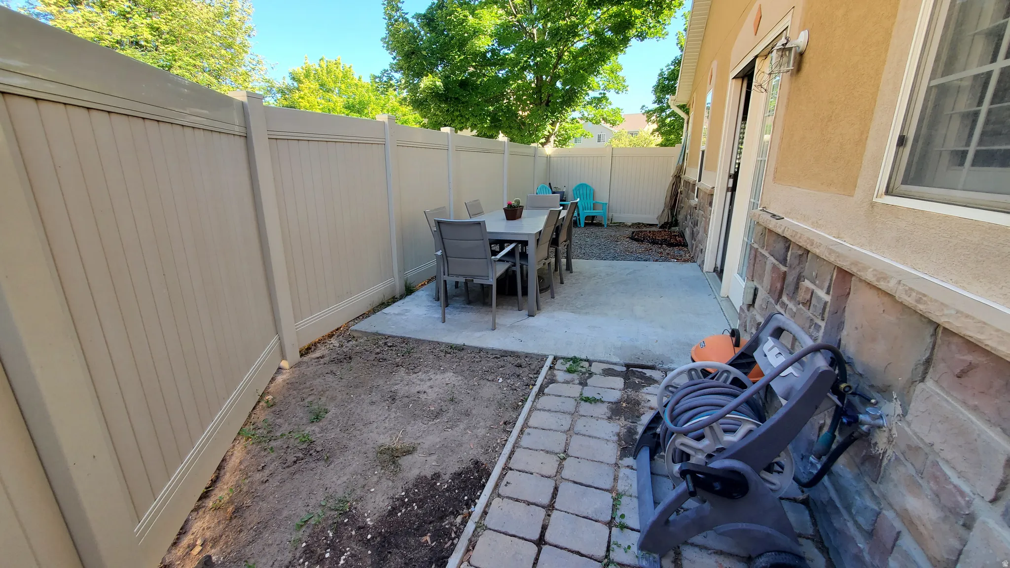 Private patio featuring a concrete slab, stone accent wall, and perimeter fencing