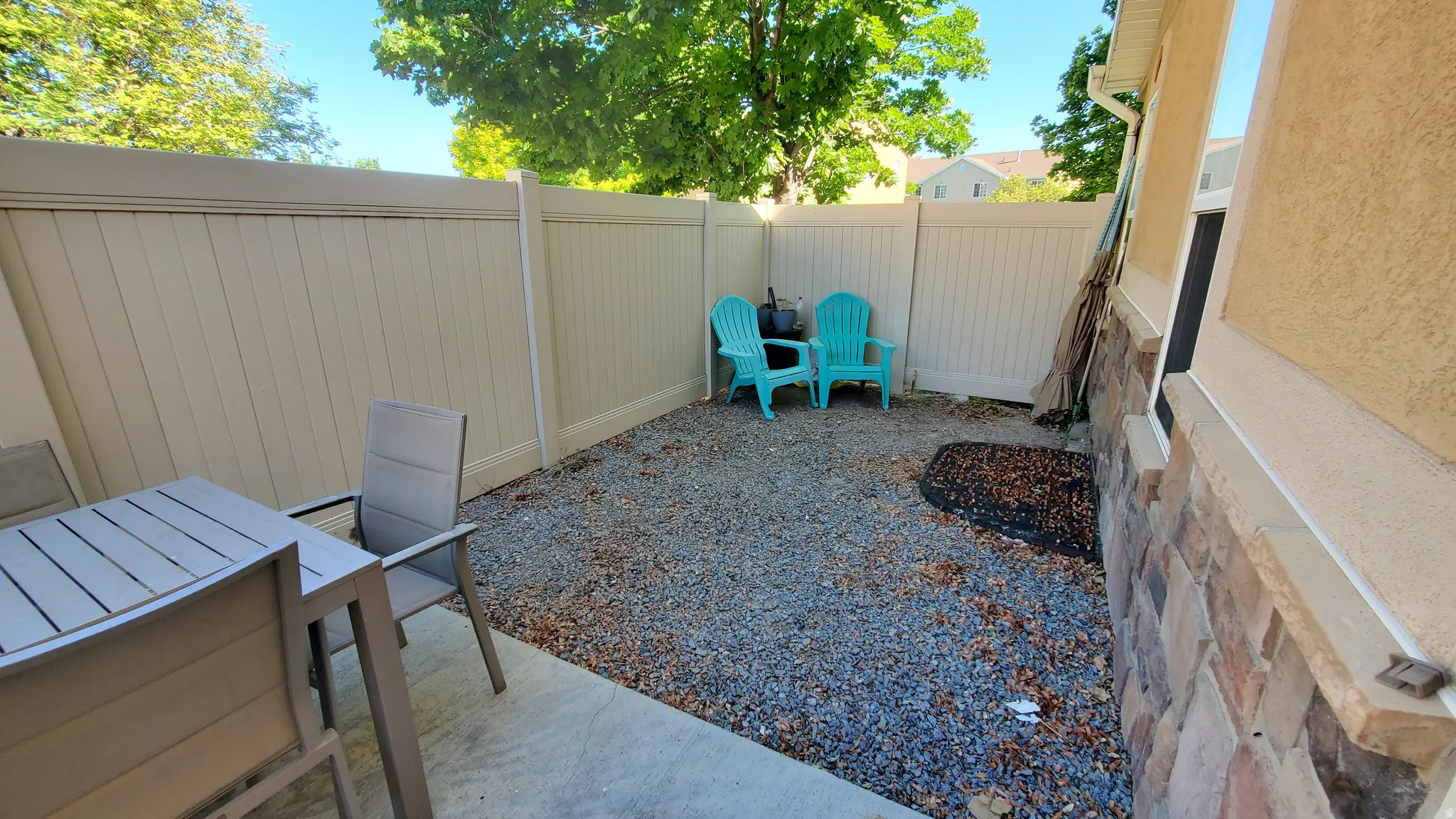 Private patio area featuring a concrete surface, gravel landscaping, and a tan privacy fence
