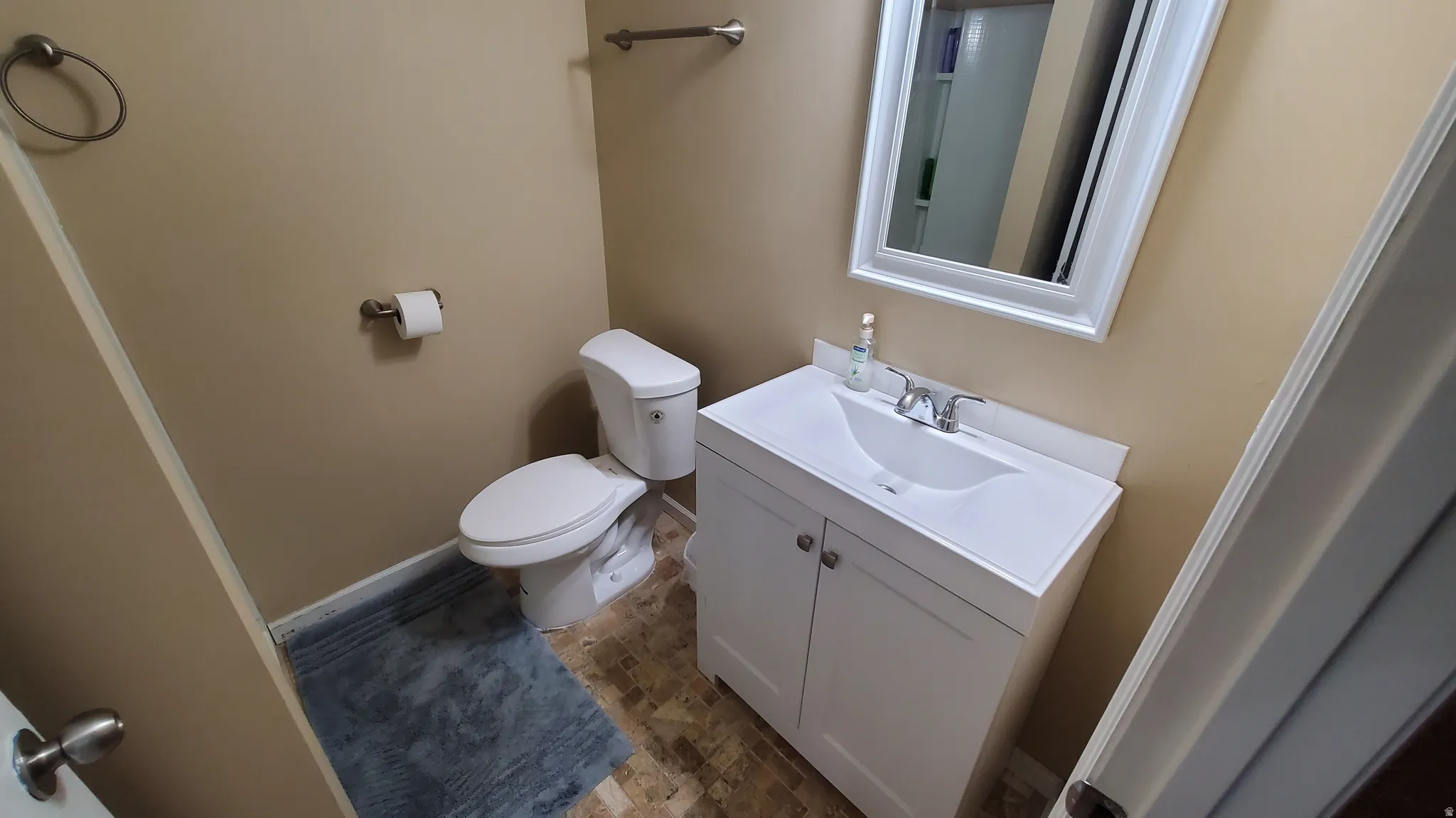 Bathroom featuring a white vanity with integrated sink, white framed mirror, and light-colored walls