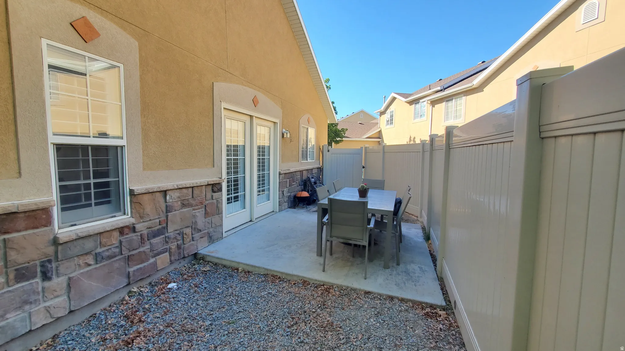 Exterior patio featuring stucco siding with a stone veneer accent, double-pane windows, and double patio doors