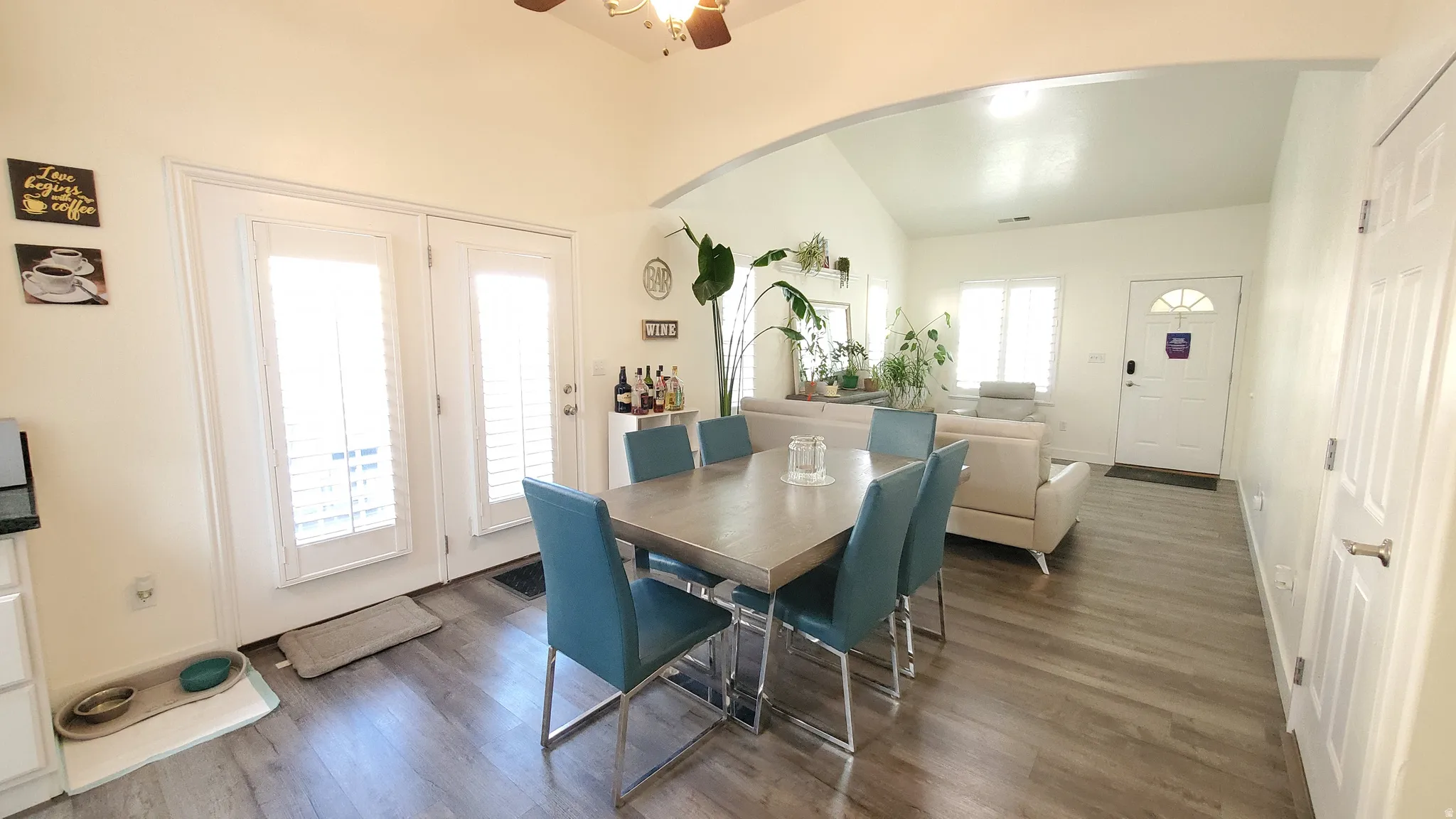 Open-concept living space with vaulted ceilings, wood-finish flooring, and bright white walls