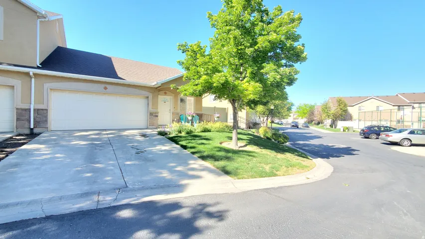 Exterior stucco finish with stone accents, featuring a two-car garage with an expansive concrete driveway