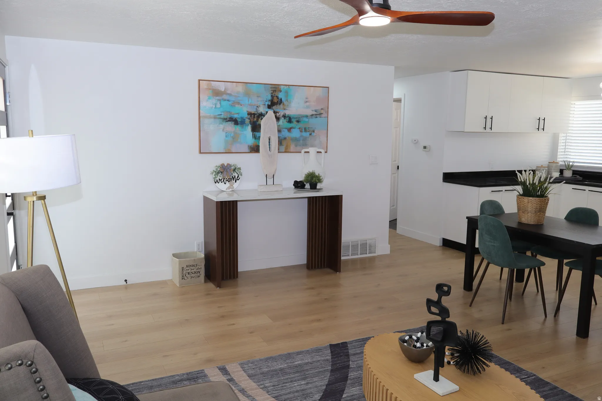 Open concept living area featuring light wood-finish flooring, white walls, and a contemporary ceiling fan