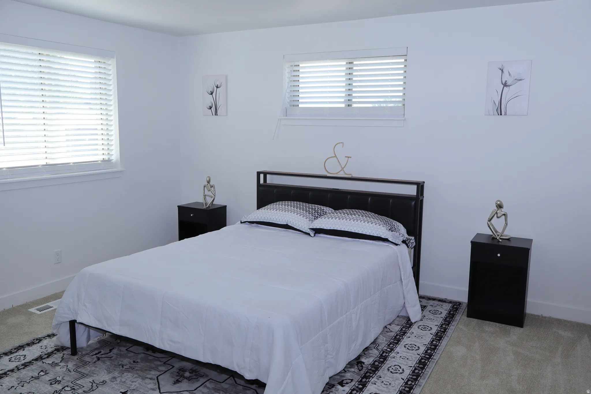 Spacious room featuring neutral carpeting, white walls, two windows with blinds, and white trim