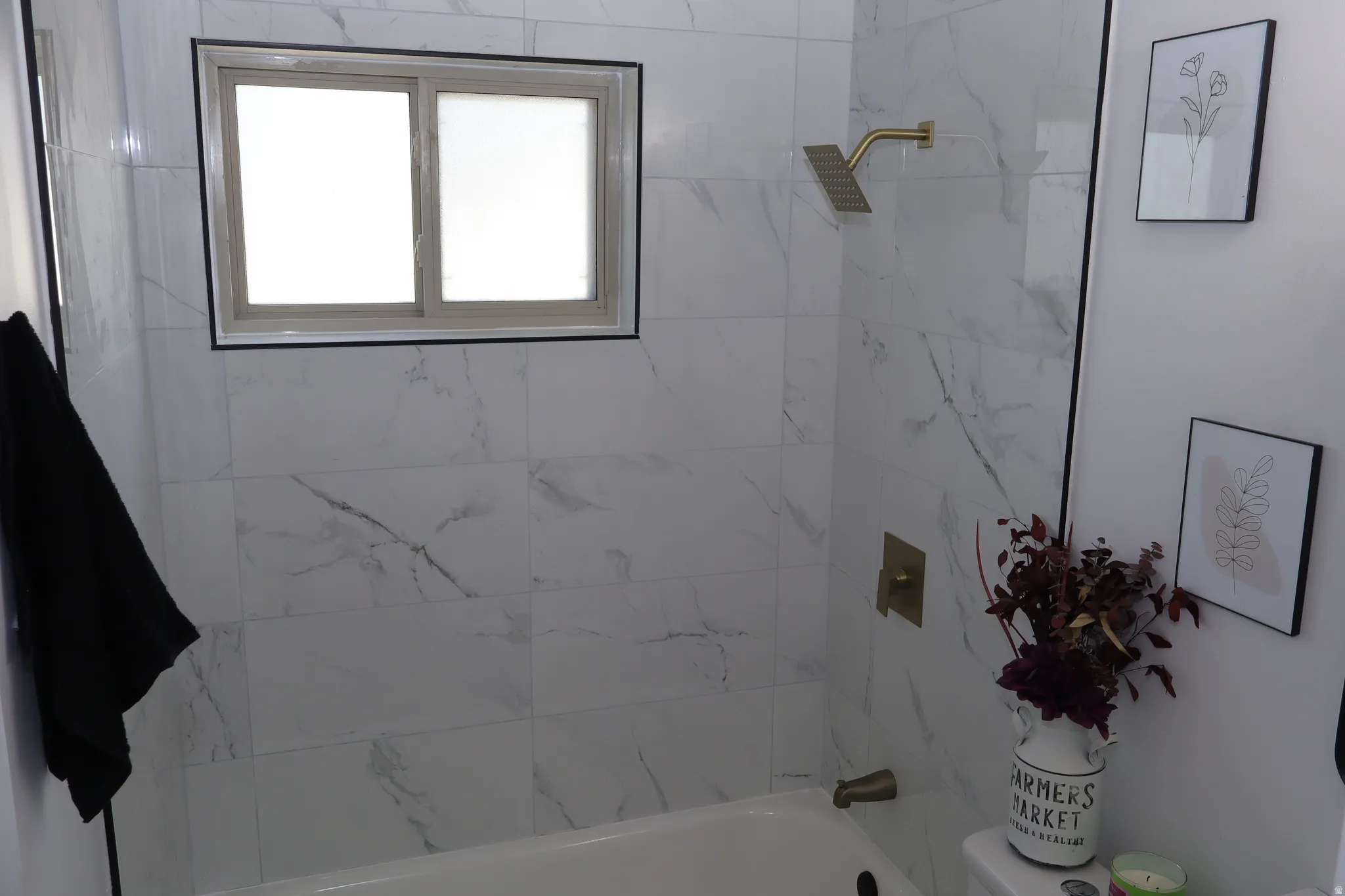 Bathtub with white marble-look tile surround and gold-finish fixtures