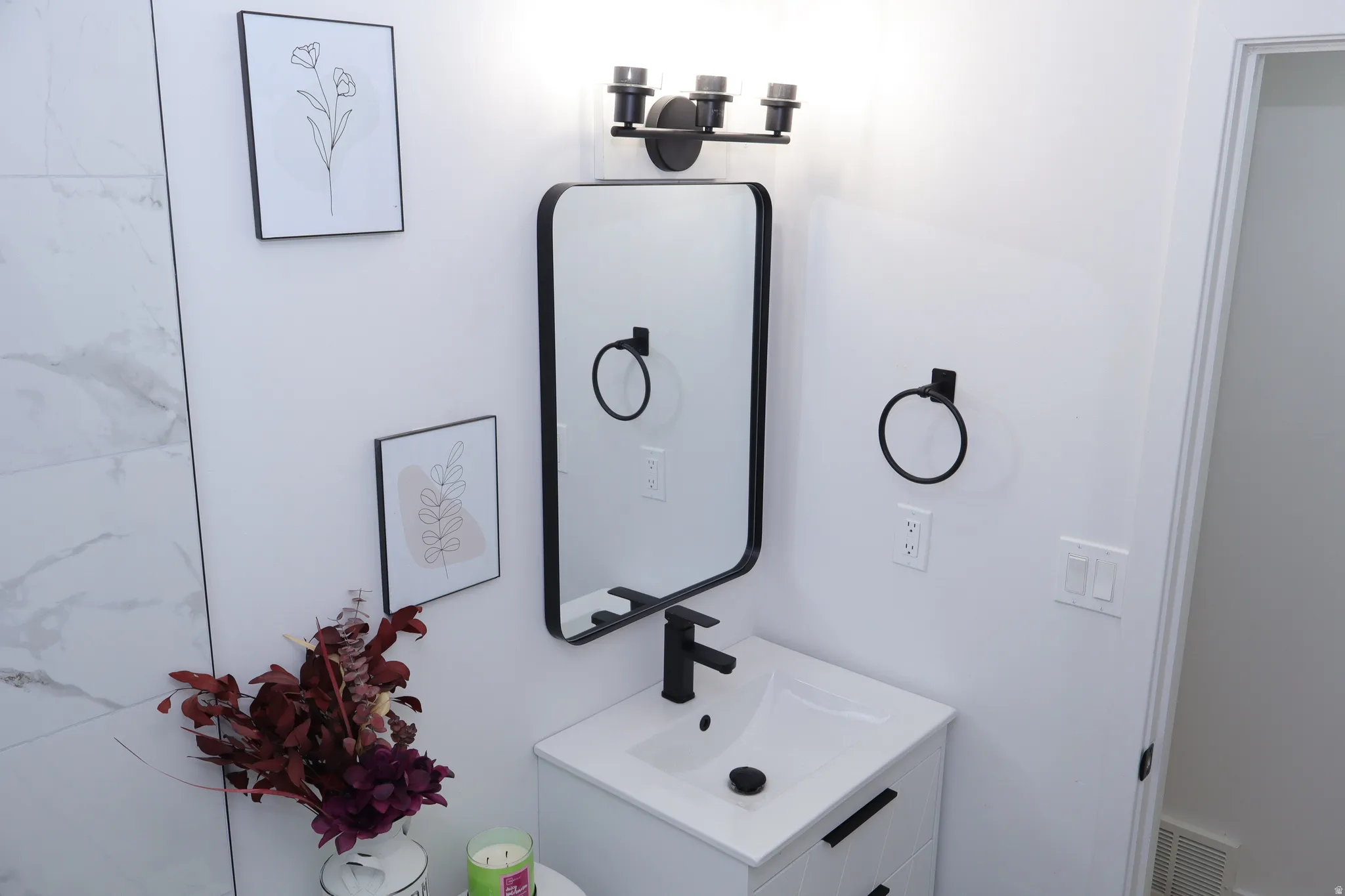 Modern bathroom vanity featuring a rectangular sink, matte black faucet, and coordinating black-framed mirror