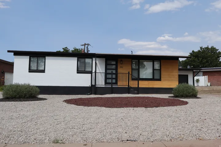 Contemporary single-story residence featuring a flat roofline and a two-tone exterior with white brick and wood-finish siding