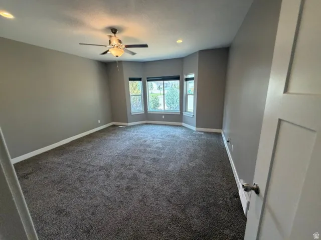 Spacious room featuring neutral carpeting, a contemporary ceiling fan, and recessed lighting