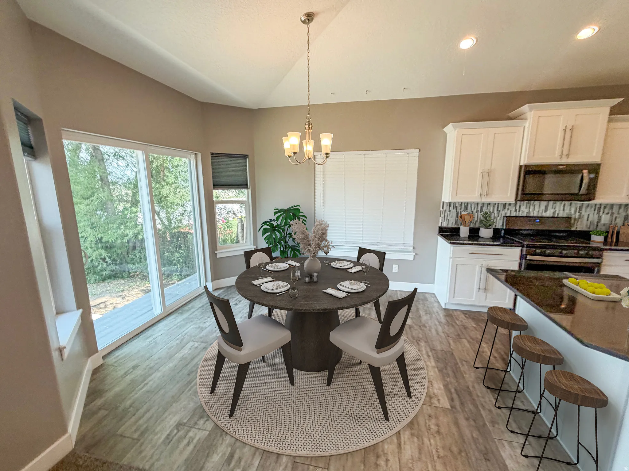 Open-concept dining area featuring wood-finish flooring, vaulted ceilings, and a contemporary chandelier