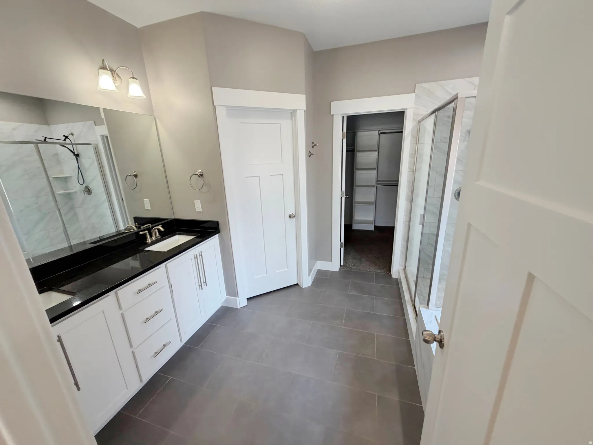 Dual vanity featuring white cabinetry, black countertops, and undermount sinks