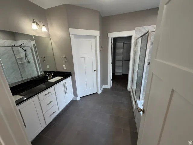 Bathroom featuring a dual vanity with white cabinetry, dark countertops, and undermount sinks