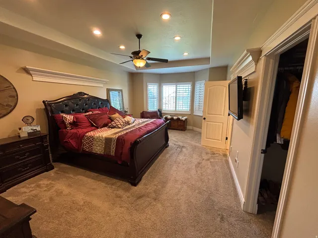 Recessed lighting illuminates the tray ceiling and carpeted flooring