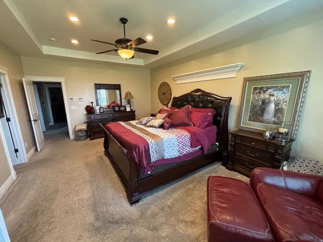 Spacious room featuring a tiered tray ceiling with recessed lighting and a ceiling fan