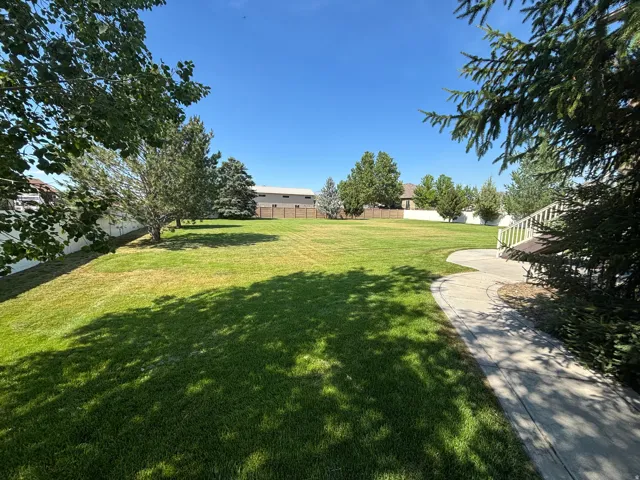 Expansive green lawn with mature trees and a curving paved pathway