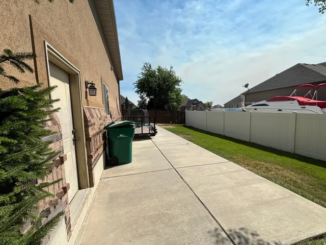 Side yard concrete pathway with a stucco exterior and brick wainscoting