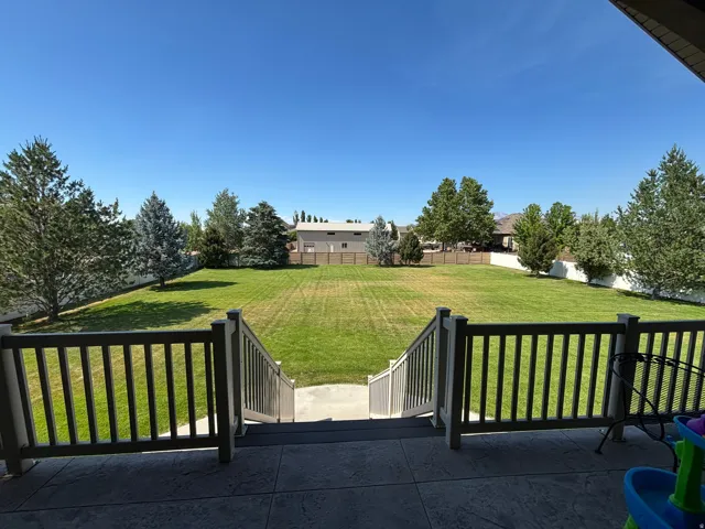 Expansive backyard featuring a manicured lawn, established trees, and a privacy fence