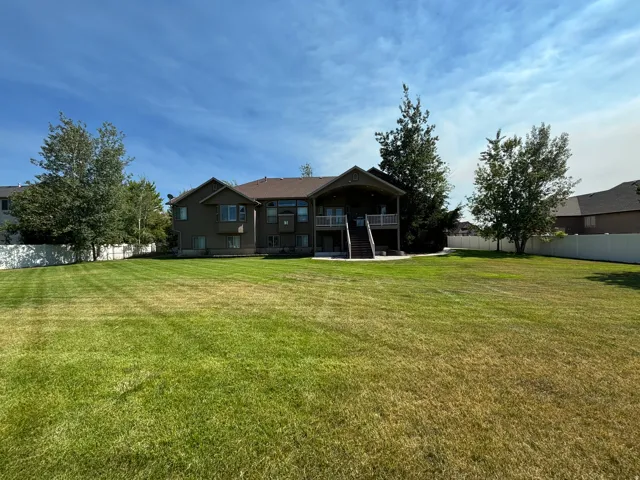 Expansive backyard featuring a manicured lawn, mature trees, and a full privacy fence
