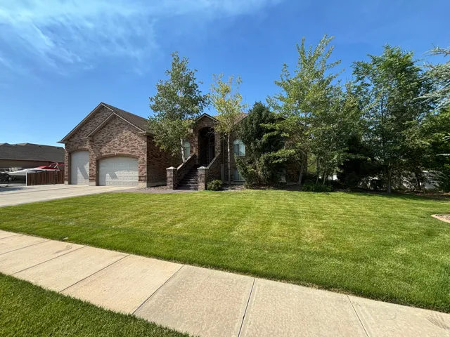 Brick exterior home featuring a two-car garage with arched doors, a dedicated front entry staircase, and a generously sized front lawn