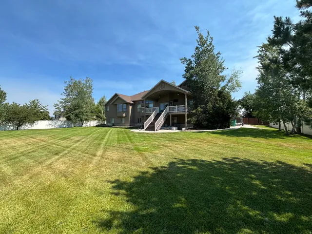 Expansive manicured lawn with mature trees and a privacy fence