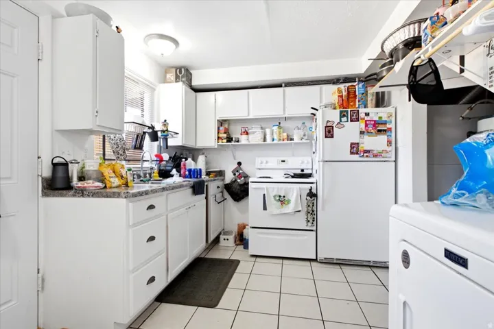 Kitchen featuring white cabinetry, a white stove, a white refrigerator, and a white washing machine