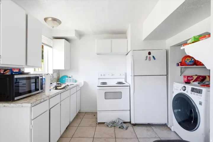 Compact kitchen area featuring white cabinetry, a white electric range, and a white refrigerator