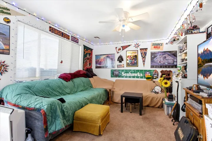 Room with light brown carpet flooring, a white ceiling with a ceiling fan, and white walls