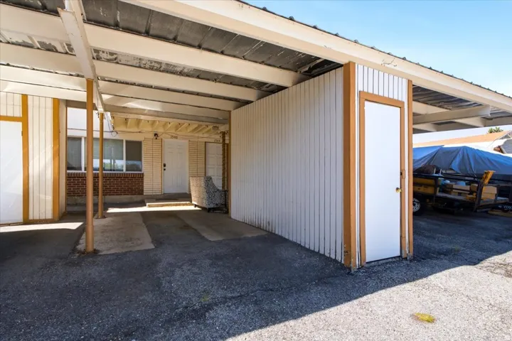 Covered carport with asphalt paving, offering sheltered parking