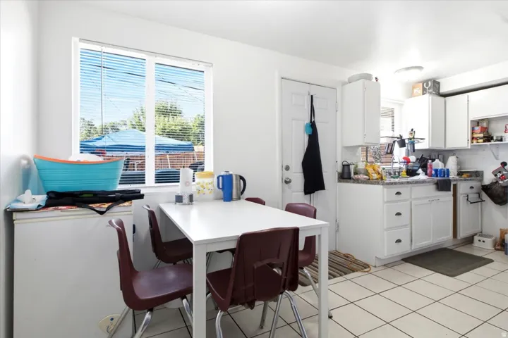 Bright kitchen with white cabinetry and a white door leading to the exterior