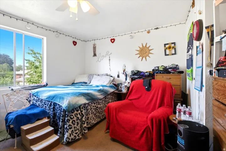 Room featuring a large window, a ceiling fan with integrated lighting, and neutral wall tones