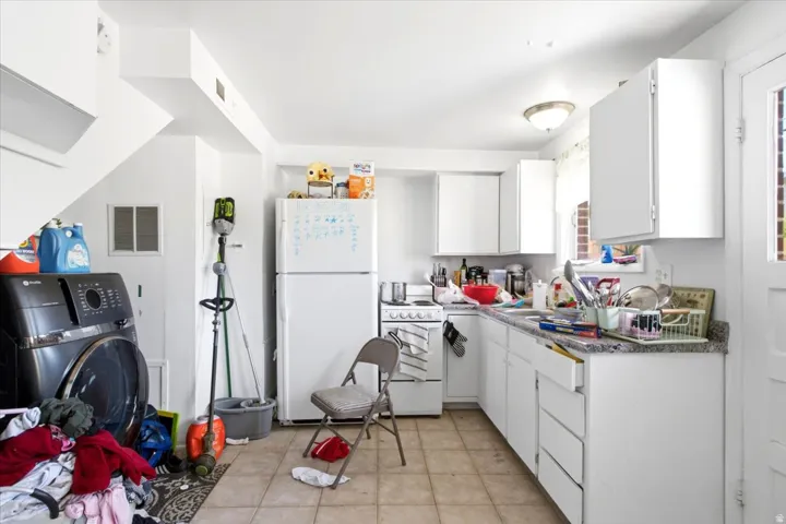 Kitchen featuring white cabinetry, a white refrigerator, and a white oven/range