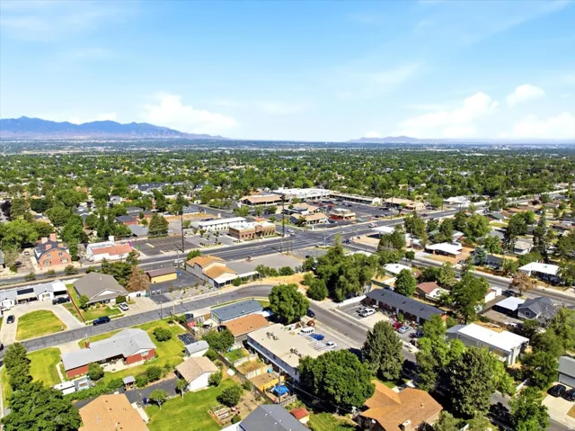 Aerial perspective showcasing an expansive residential area with abundant mature trees and distant mountains