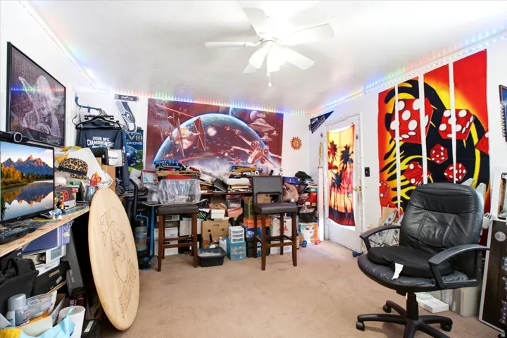 Carpeted room featuring a ceiling fan, white walls, and a white door frame