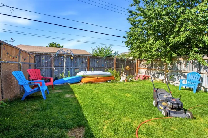 Fenced backyard featuring mature landscaping, a manicured lawn, and a wooden privacy fence