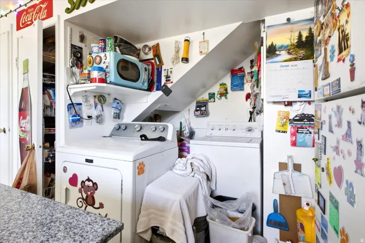 Dedicated laundry area featuring a white washing machine and dryer, built-in shelving, and recessed space under a staircase