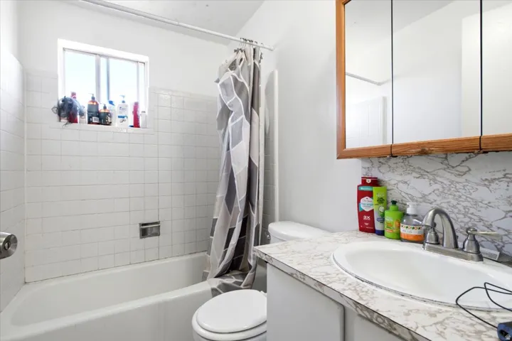 Full bathroom featuring a white tub, white subway tile surround, and a window above the tub