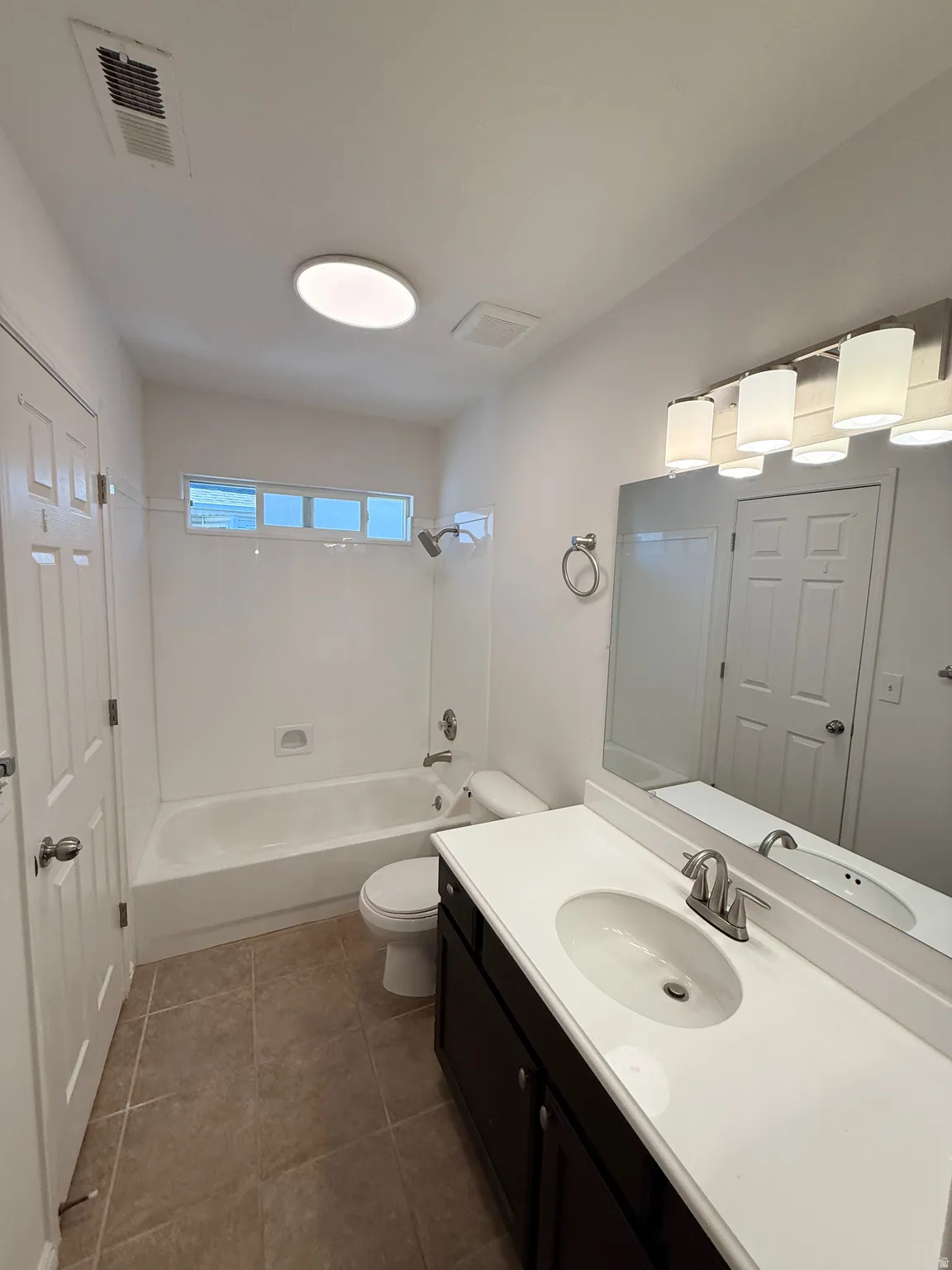 Bathroom featuring a single vanity, undermount sink, dark wood-finish cabinetry, and a shower-tub combination