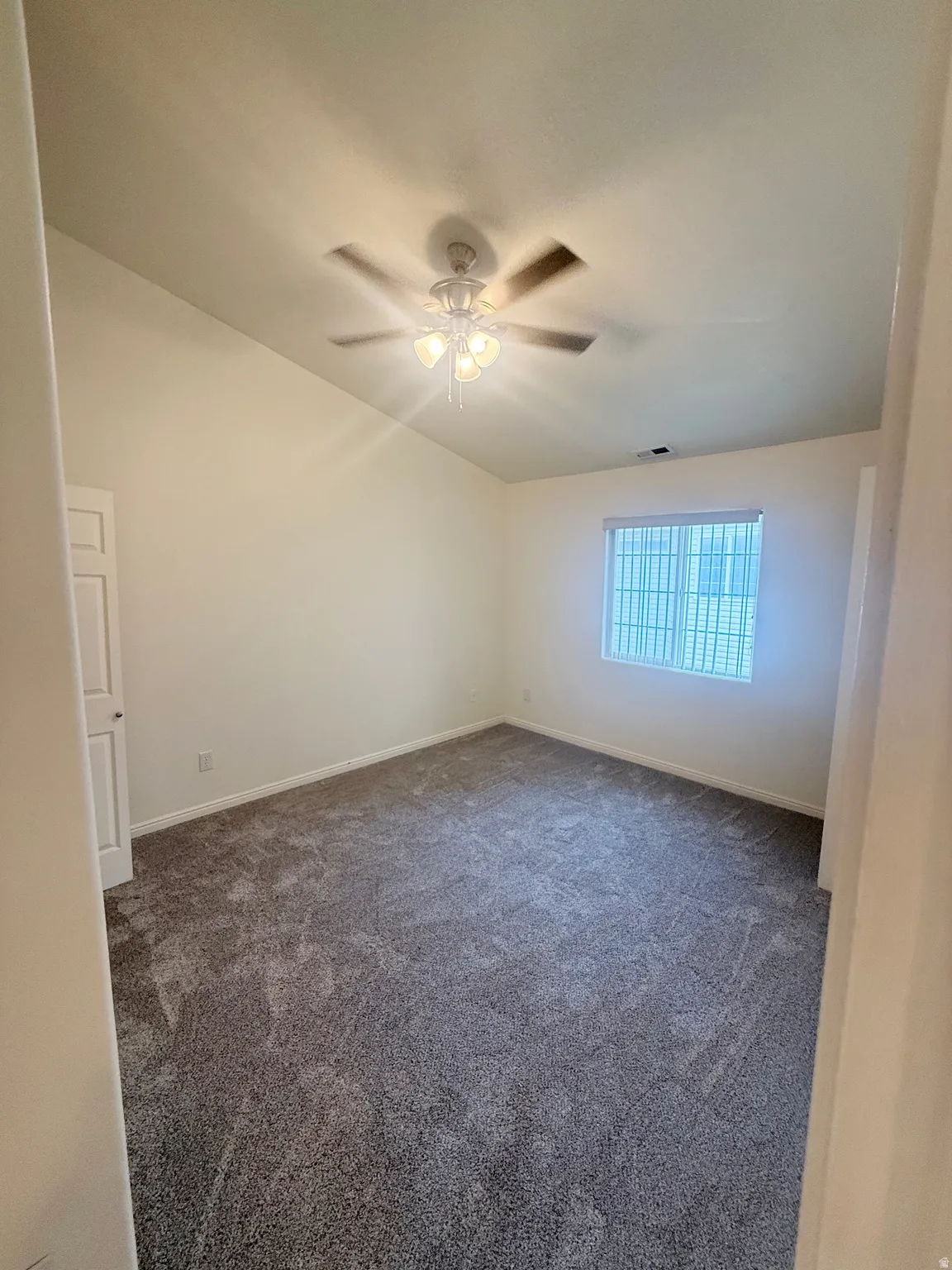 Spacious interior room with vaulted ceilings and a ceiling fan with integrated lighting