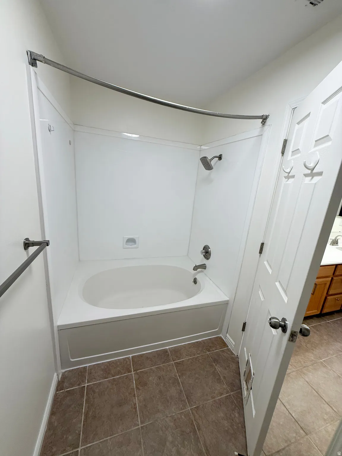 Soaking tub with integrated shower, white panel shower surround, brushed nickel fixtures, and square tile flooring