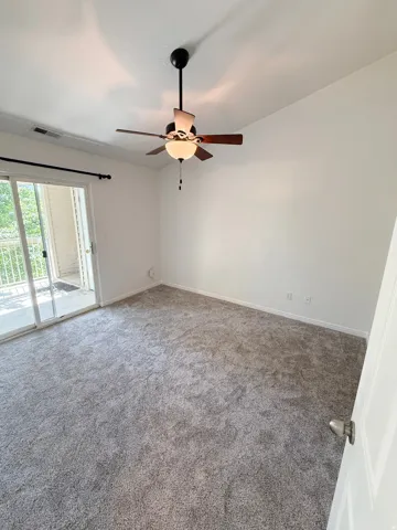 White walls, gray carpeting, and a ceiling fan with integrated lighting