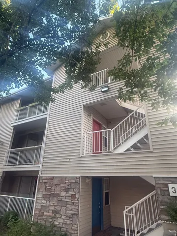 Multi-story building featuring horizontal siding, stone veneer accents, and multiple balconies with white railings