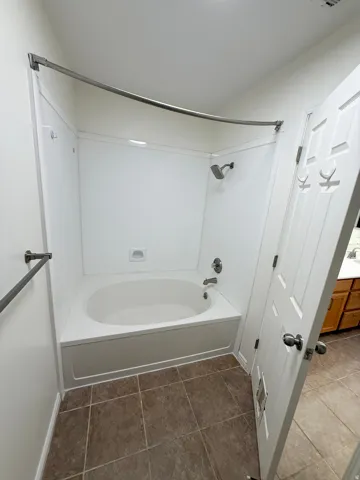 Soaking tub with integrated shower, white panel shower surround, brushed nickel fixtures, and square tile flooring