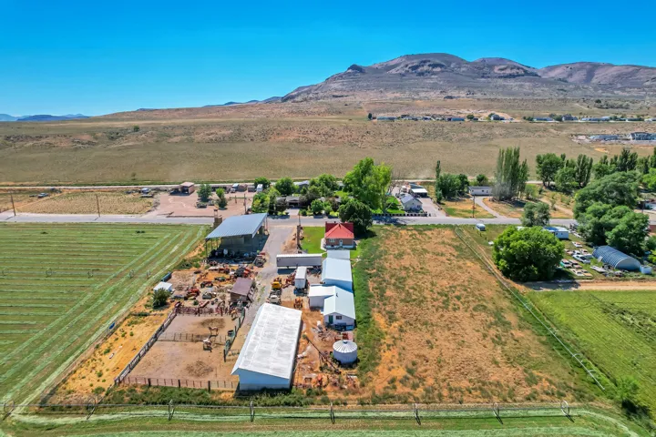 Expansive property featuring multiple outbuildings, fenced enclosures, open fields, and a prominent red-roofed residence