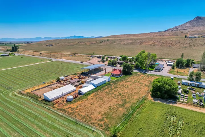 Expansive agricultural property featuring multiple outbuildings, fenced enclosures, and cultivated fields