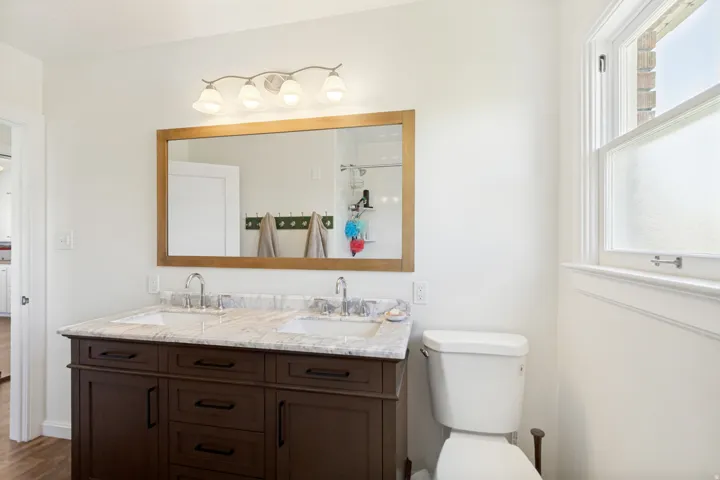 Double vanity with a granite countertop, dual undermount sinks, and dark wood cabinetry