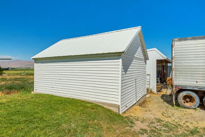 White-sided outbuilding with a metal roof, set on a concrete foundation