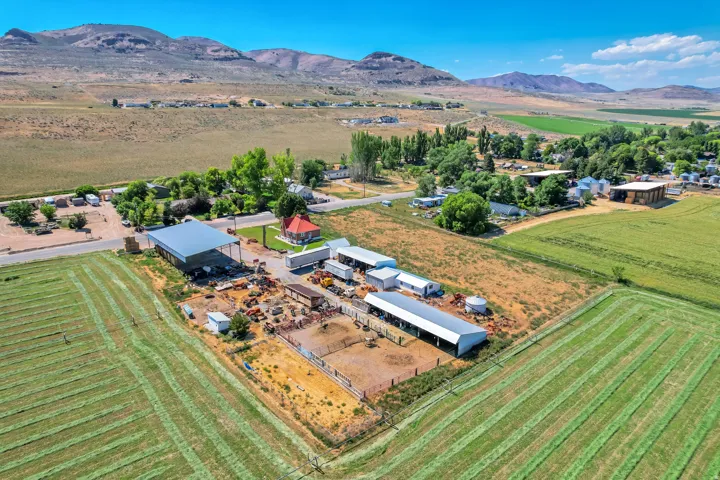 Expansive rural property featuring multiple agricultural structures, cultivated fields, and mountainous terrain in the background