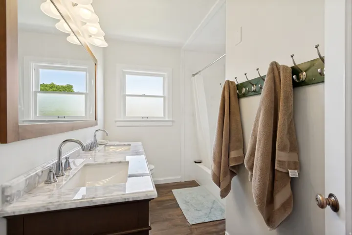 Bathroom vanity featuring dual under-mount sinks, a polished stone countertop, and chrome fixtures
