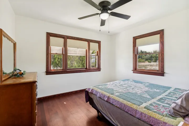 Room featuring wood-finish flooring, white walls, and a ceiling fan with integrated lighting